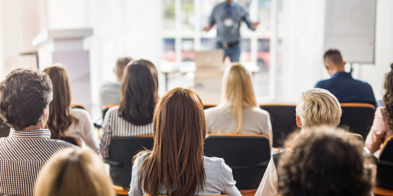 Back view of large group of business people having a training class in a board room.